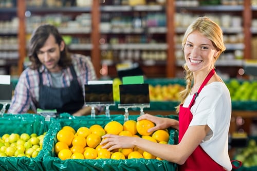 Portrait of smiling female staffs checking fruits in organic section of supermarket
