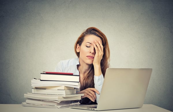 Too much work tired sleepy young woman sitting at her desk with books in front of laptop computer isolated grey wall office background. Busy schedule in college, workplace, sleep deprivation concept